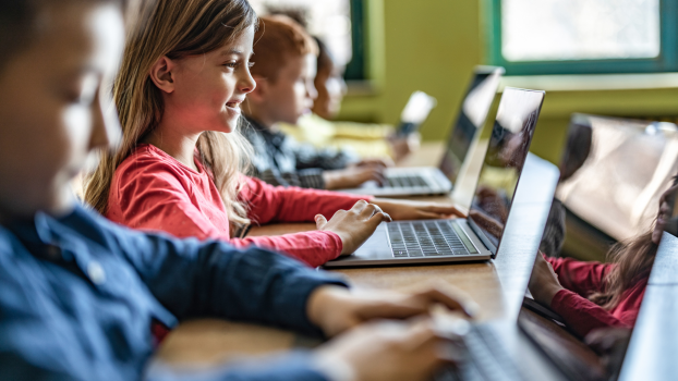 Estudantes do ensino fundamental usam computadores individualmente durante uma aula.