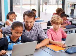 Estudiantes en clase con computadoras portátiles.